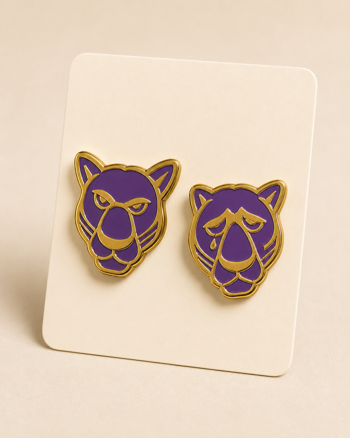 Two enamel lapel pins, the Panther comedy and tragedy masks, in purple and gold on a backing card.